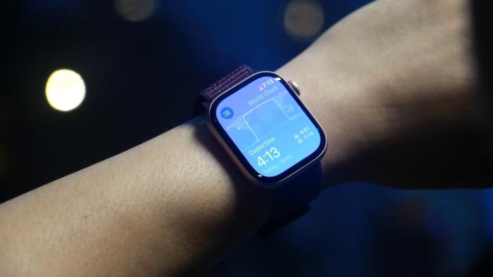 The Apple Watch Series 10 with the World Clock app open on its home screen, worn on a wrist held in mid-air.